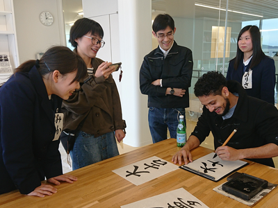 Participants trying calligraphy with high school students